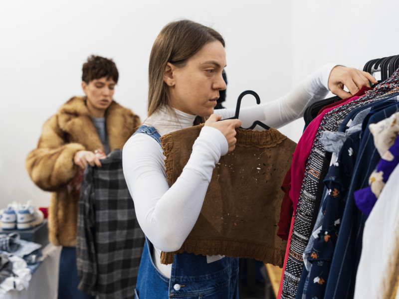 Djevojka pregledava second hand odjeću na stenderu